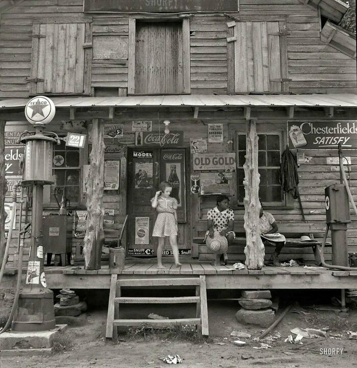Vintage black and white photo of people on the porch of a rural general store, moments lost to history.