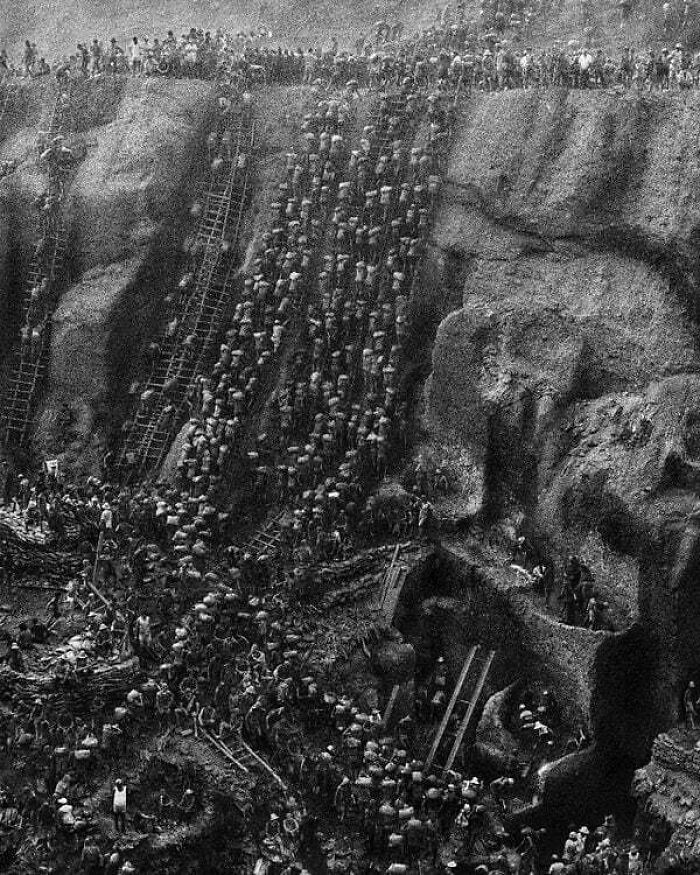 Hundreds of people ascending a steep quarry on ladders, a moment nearly lost to history.