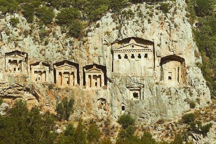 Ancient rock-cut tombs carved into a cliff face, a historical moment of architectural ingenuity nearly lost to history.