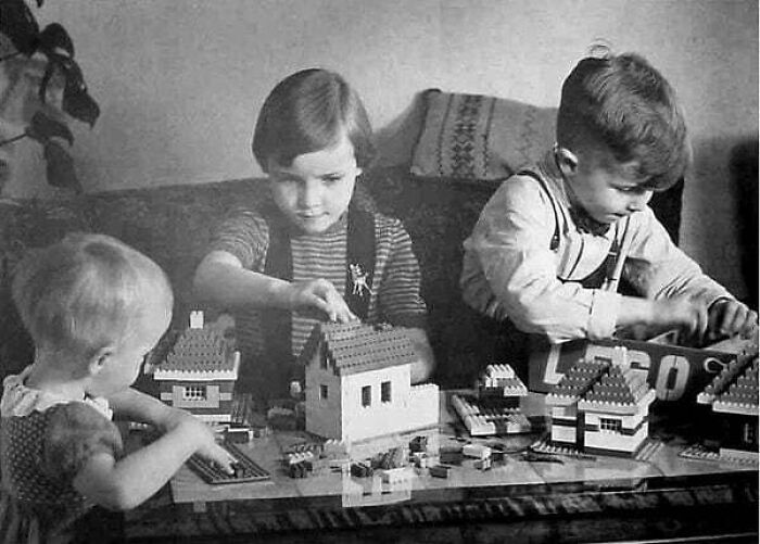 Three children playing with Lego houses on a table, a cherished moment nearly lost to history.