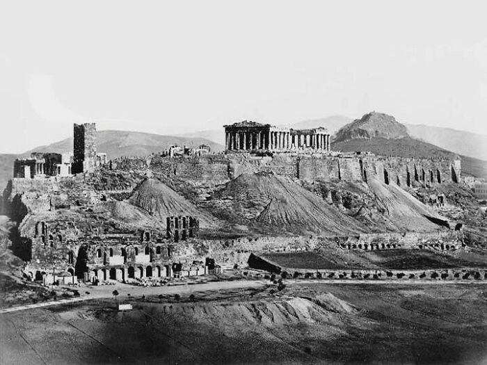 A black and white wide shot of the Acropolis of Athens, showing the Parthenon and surrounding ancient structures, a historical moment nearly lost to history.