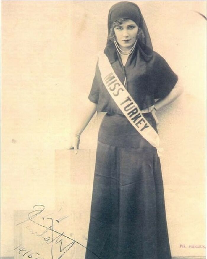 Miss Turkey in a head covering and sash, posing for a photograph, a moment nearly lost to history.