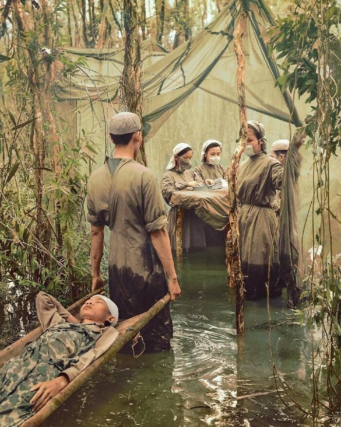 A colorized photo of a military medic carrying a wounded soldier through a flooded jungle, with other medics in a tent, a moment nearly lost to history.
