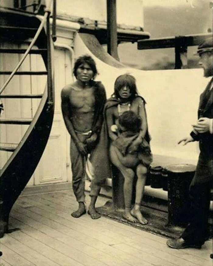 A black and white photo of three Indigenous people, two adults and one child, standing on a boat deck, a moment nearly lost to history.