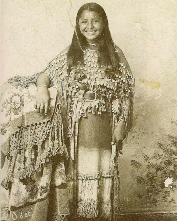 A smiling young Native American woman in traditional clothing, a moment nearly lost to history.
