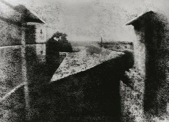 A blurry, grainy black and white photo capturing the world's first photograph, a moment from history.