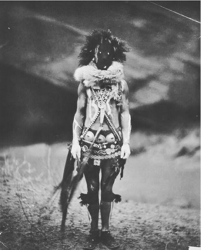A black and white image of a person in traditional elaborate attire, a captivating moment from history.