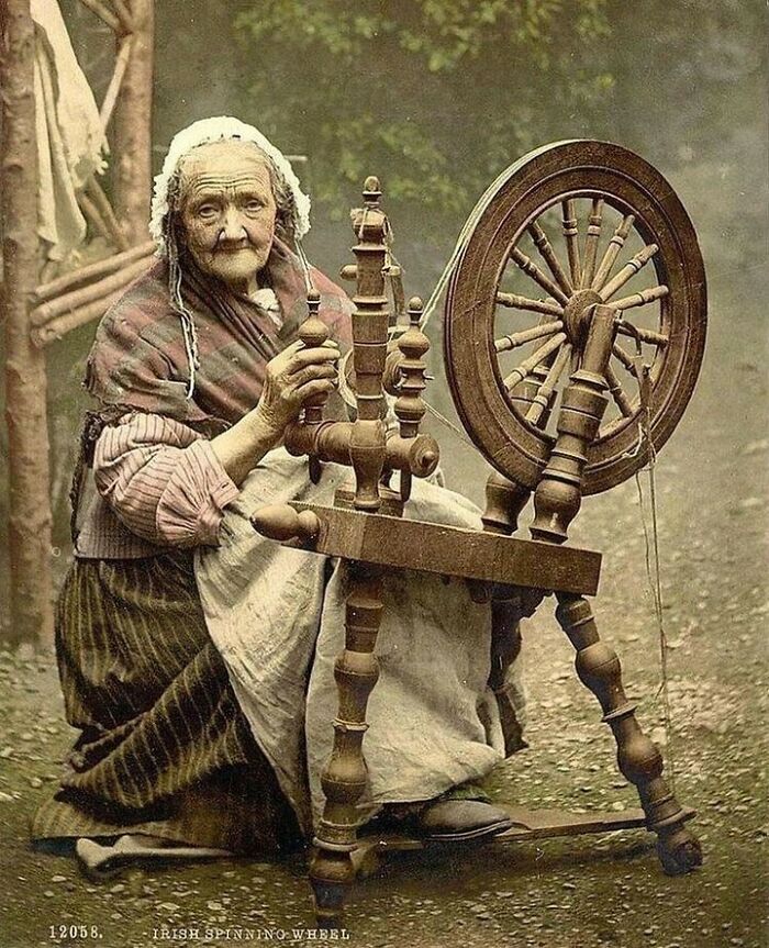 An elderly woman operates an Irish spinning wheel outdoors, depicting moments nearly lost to history.