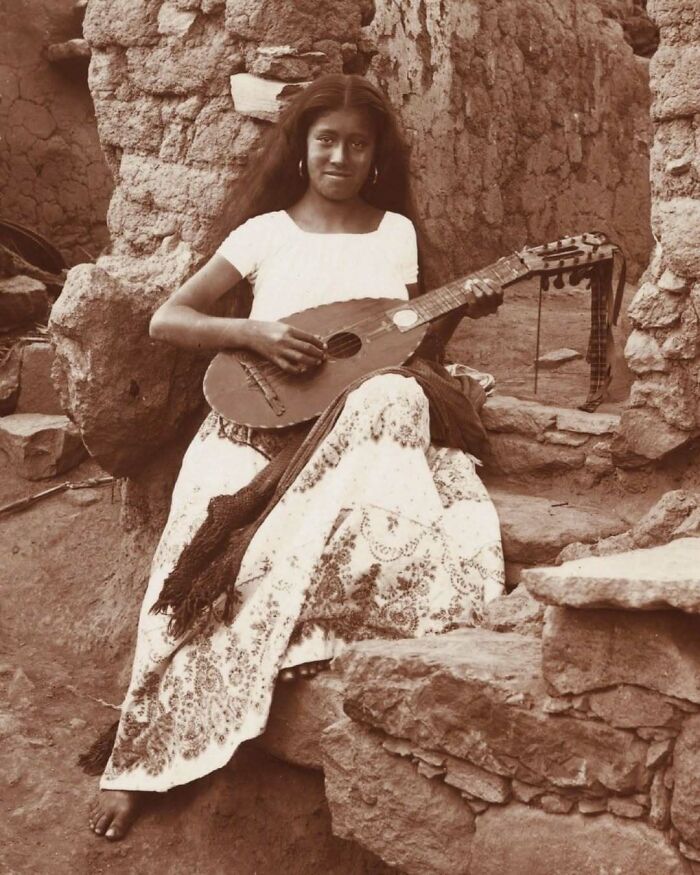 A woman in traditional dress plays a stringed instrument, a moment nearly lost to history.