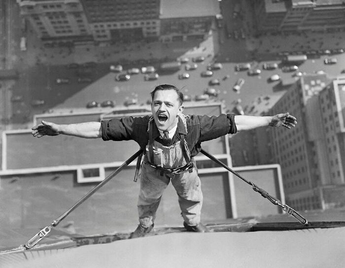 A man with arms outstretched, suspended high above a city street, captures a moment nearly lost to history.