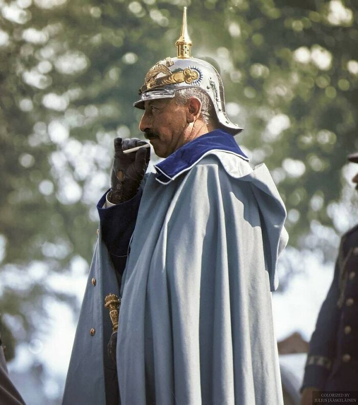A distinguished man in a detailed military helmet and cape, smoking a cigarette, a moment nearly lost to history.