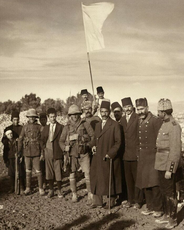 Historic image of diverse military and civilian figures with a white flag, a significant moment nearly lost to history.