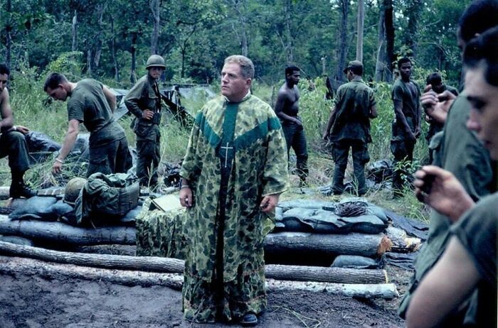A chaplain in camouflage robes stands among soldiers in a jungle, a moment nearly lost to history.