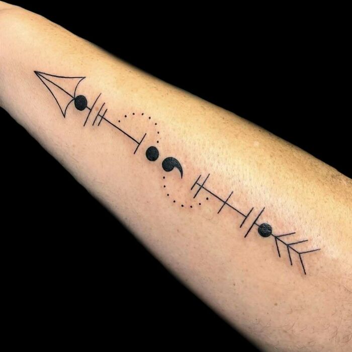 An arrow tattoo with a semicolon in the center, representing a powerful story of overcoming challenges.