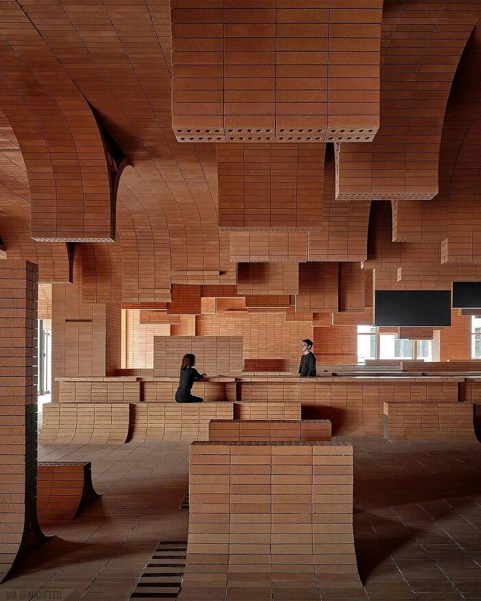 Brilliant and beautiful designs: People sitting in an intricately designed room with layered brick structures forming walls and ceilings.