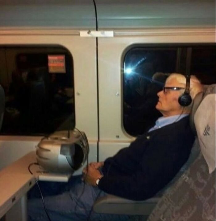An older man with headphones listening to a portable CD player on a train, an unexpected moment that makes his day interesting.