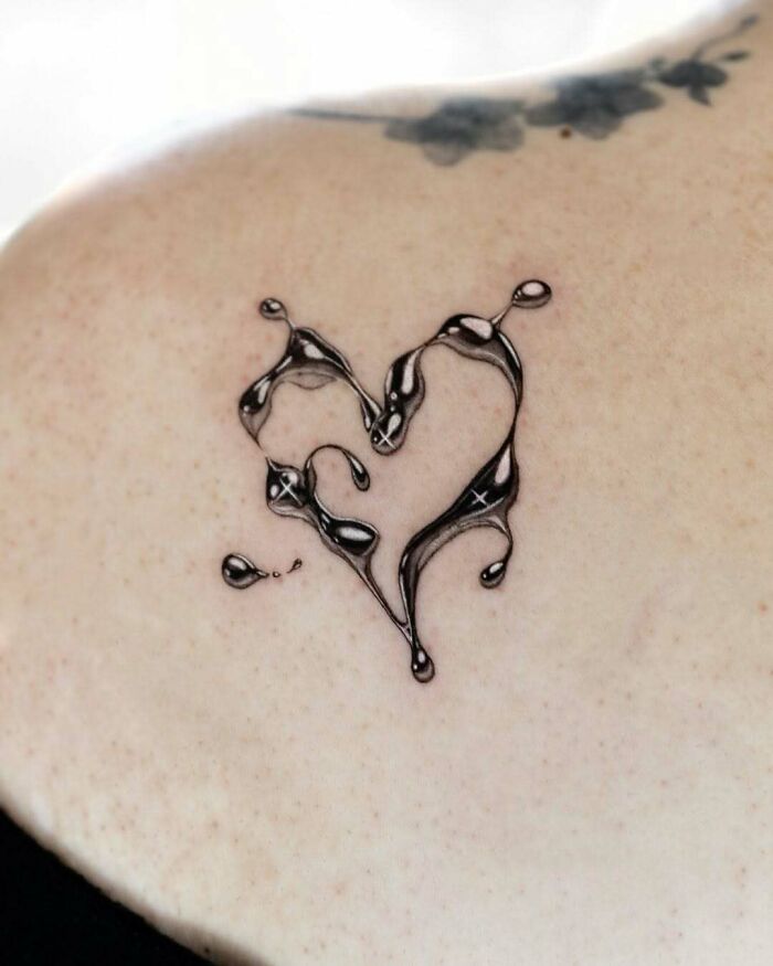 Abstract heart tattoo ideas for women, featuring a glossy, dripping liquid heart design on the shoulder.