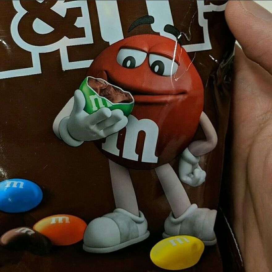 A cursed image on an M&Ms bag showing the red M&M character eating a green M&M, a disturbing visual.