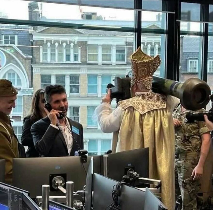 An unhinged, cursed image of a man in religious garb holding a rocket launcher, next to a man on the phone.