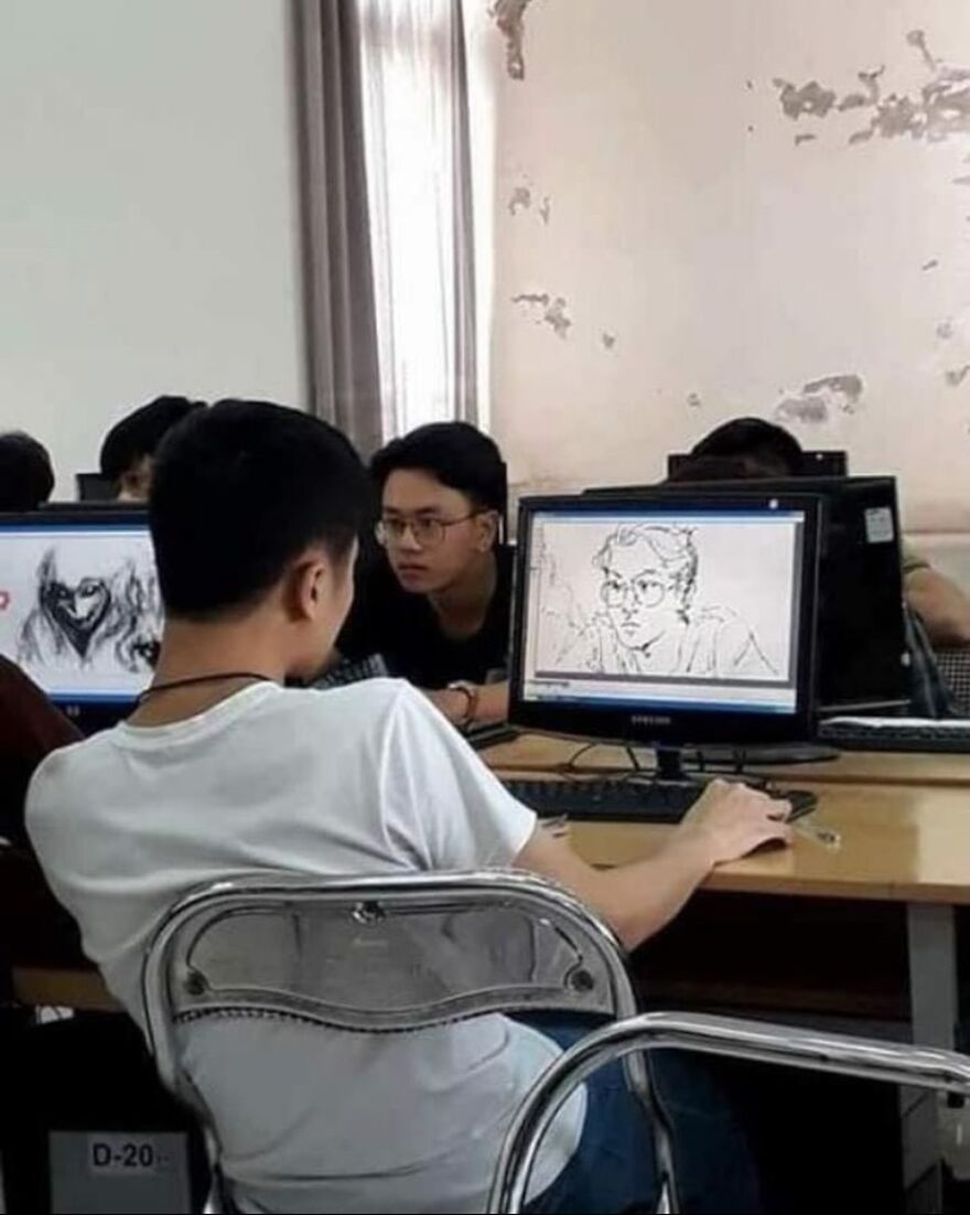 Two students in a computer lab, one looking at the other's monitor displaying a drawing, a random and unhinged image.