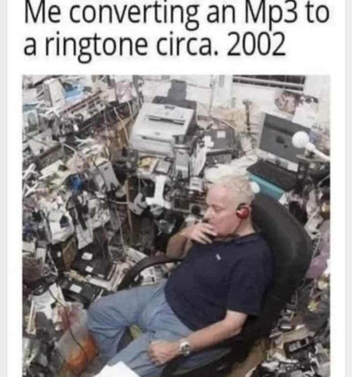 A man wearing headphones in a cluttered room filled with computers and wires, a nostalgia gem.