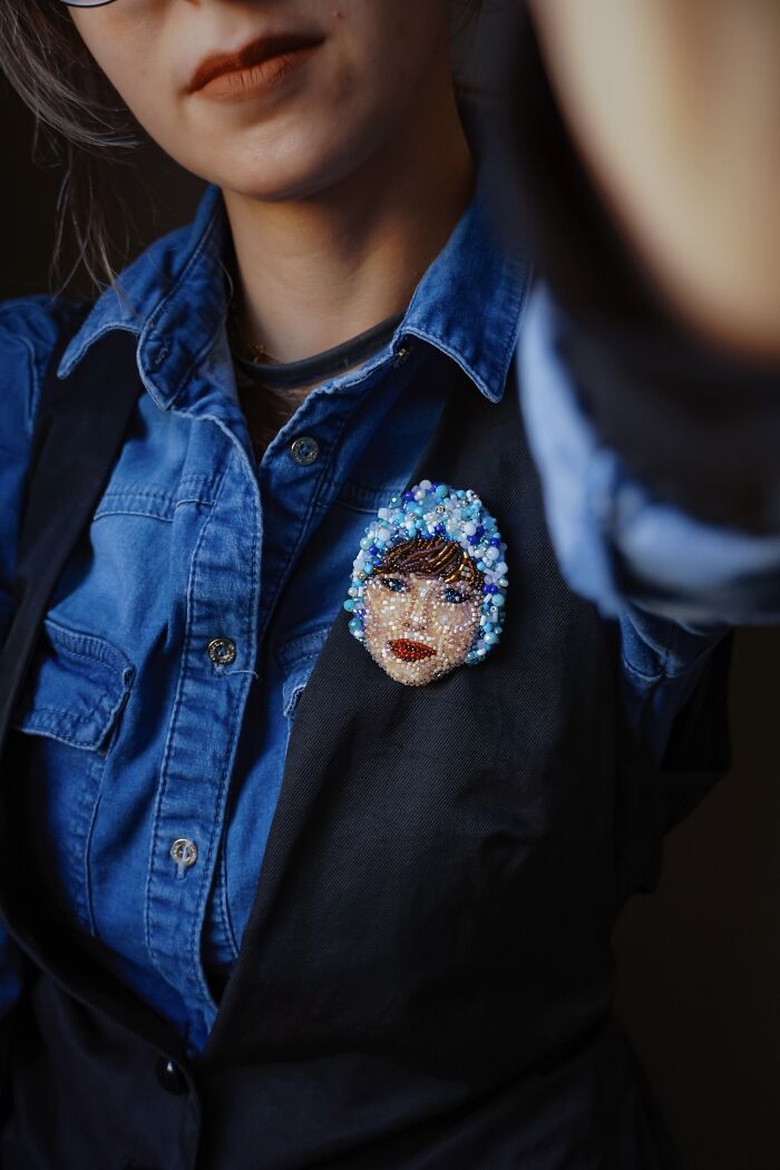 Woman wearing a beaded creation by Tiffany Pisani, a unique brooch in the shape of a face on her denim shirt.