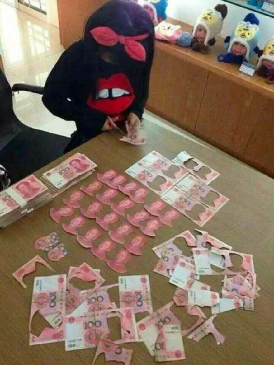 A person cutting up money on a table, an unhinged and cursed image.