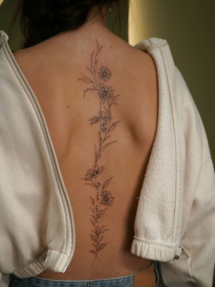 Spinal floral tattoo ideas for women, an elegant line art design on a back.