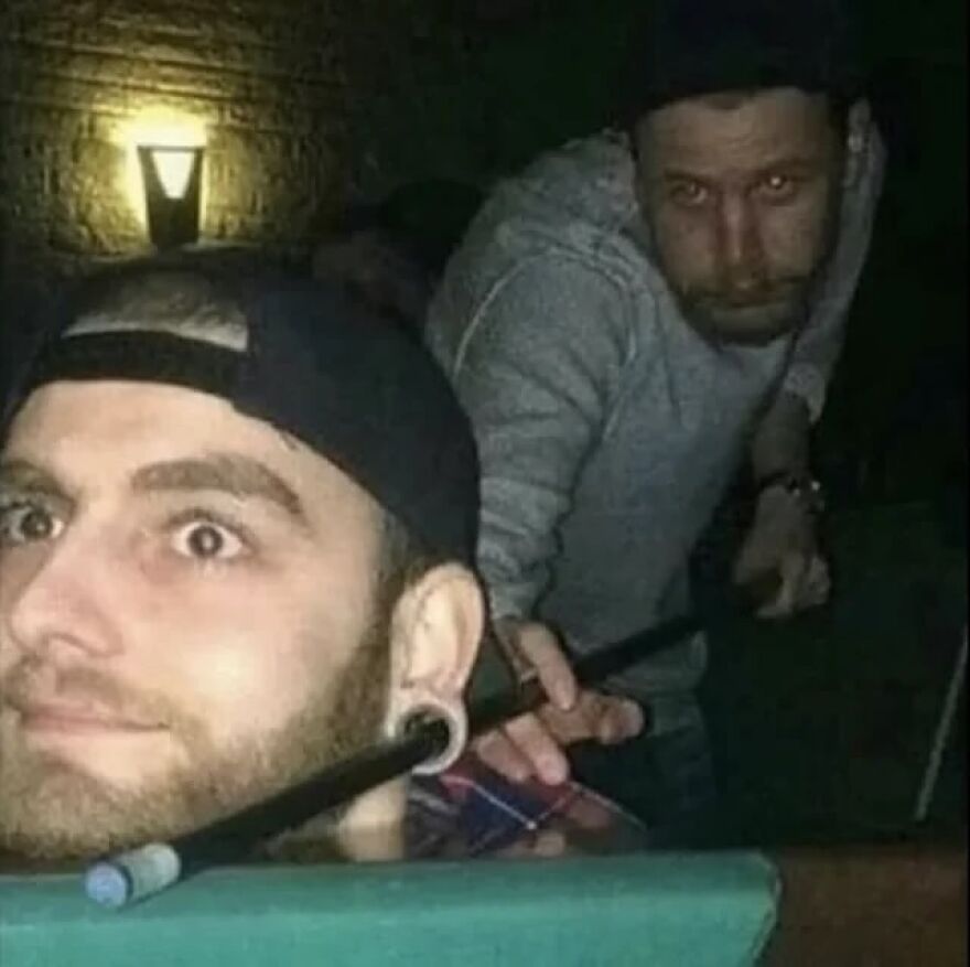 Two men playing pool, one appearing to use the other's head for a shot, an unhinged and cursed image.