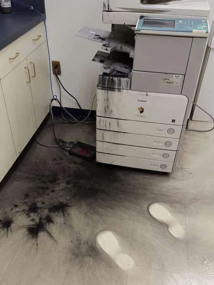 A printer mess with toner spilled everywhere and white footprints, a cursed image of office mishap.