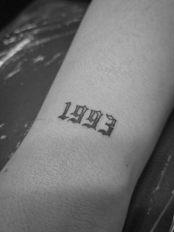 Small, gothic font 1993 tattoo ideas for women on the wrist, a popular tattoo design.