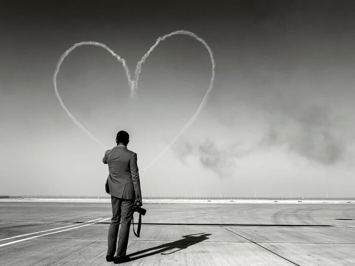 Remarkable photograph by Tittu Shaji Thomas capturing life across cultures and landscapes: a man watching a heart in the sky.