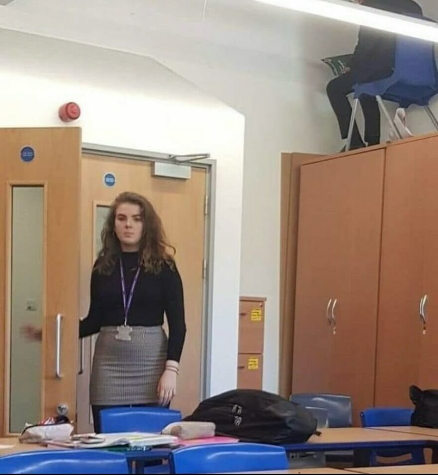 A student sitting on top of a cabinet in a classroom, adding to the collection of cursed images.