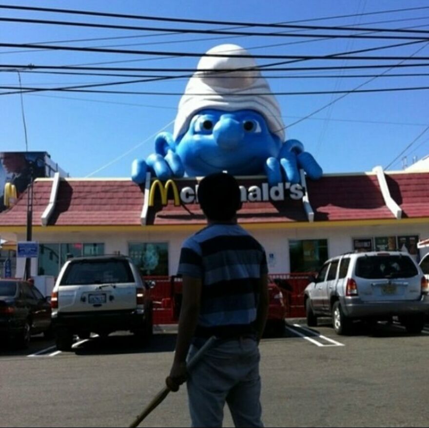 A giant Smurf figure on top of a McDonald's restaurant, creating a bizarre and cursed image.
