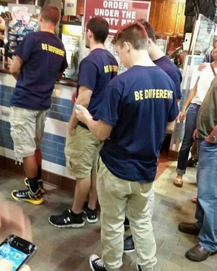 Four men wearing identical BE DIFFERENT t-shirts, a random and unhinged image.