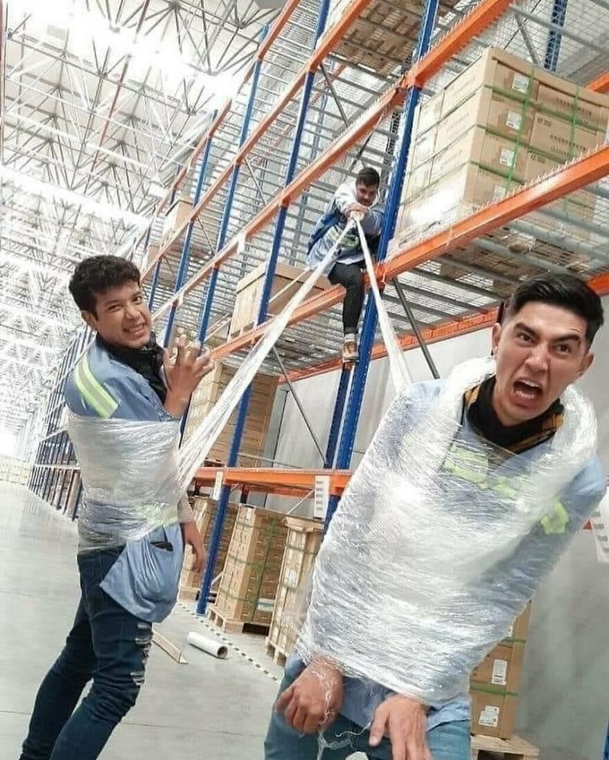 Warehouse workers wrapped in plastic, creating a cursed and unhinged scene.