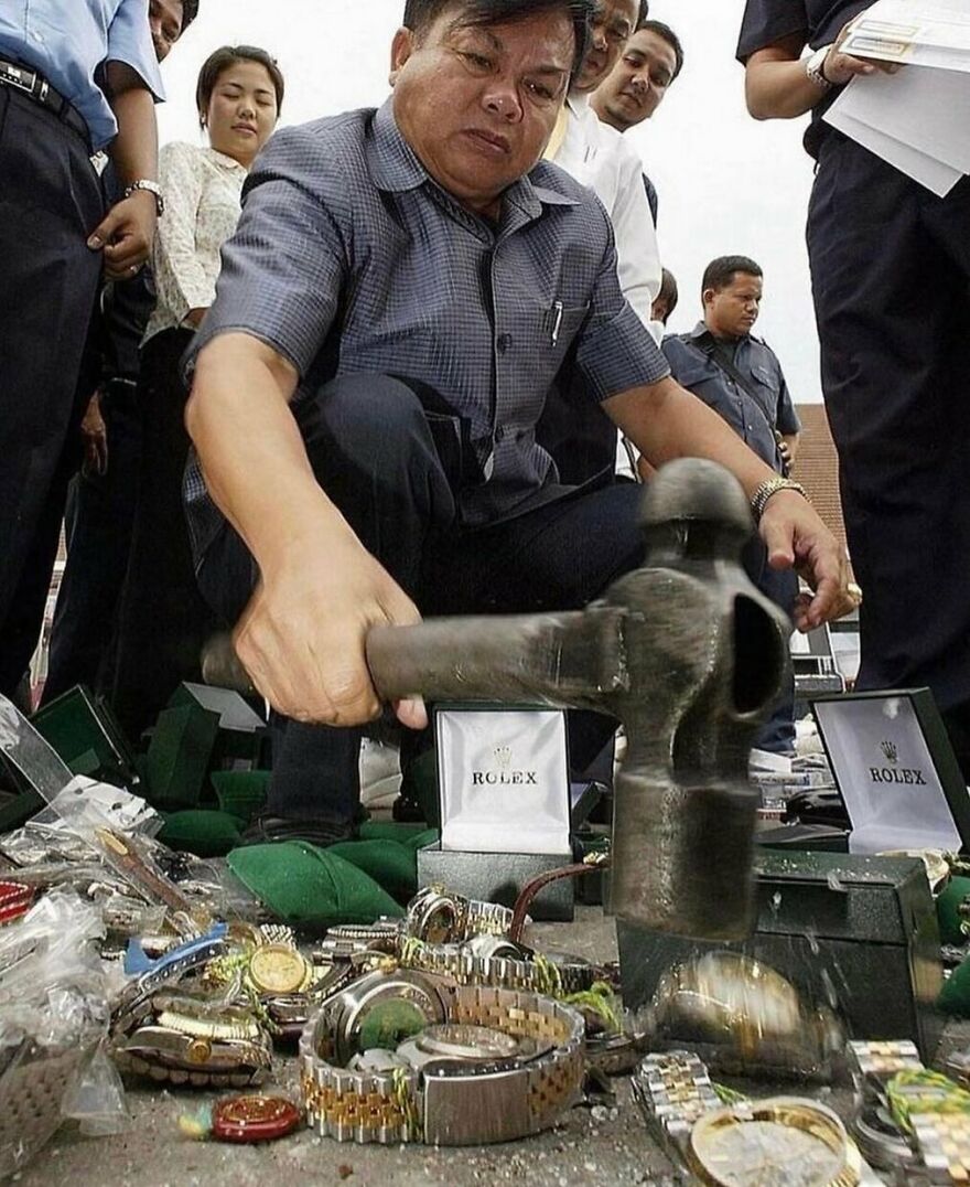 A man smashing replica Rolex watches with a hammer, a random and unhinged moment.