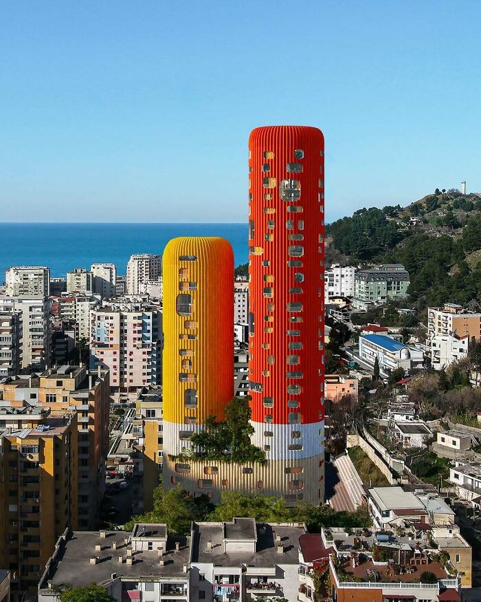 Two tall, cylindrical buildings in red and yellow, featuring brilliant and beautiful architectural designs overlooking a city.