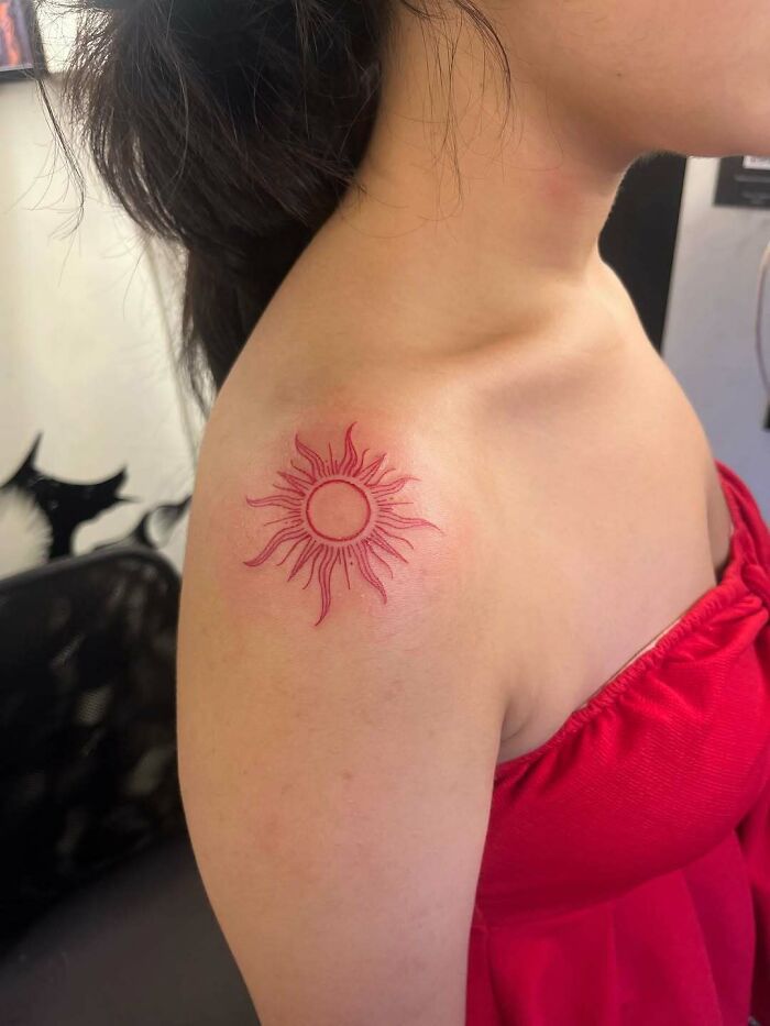 Vibrant red sun shoulder tattoo ideas for women, a bold and radiant choice.