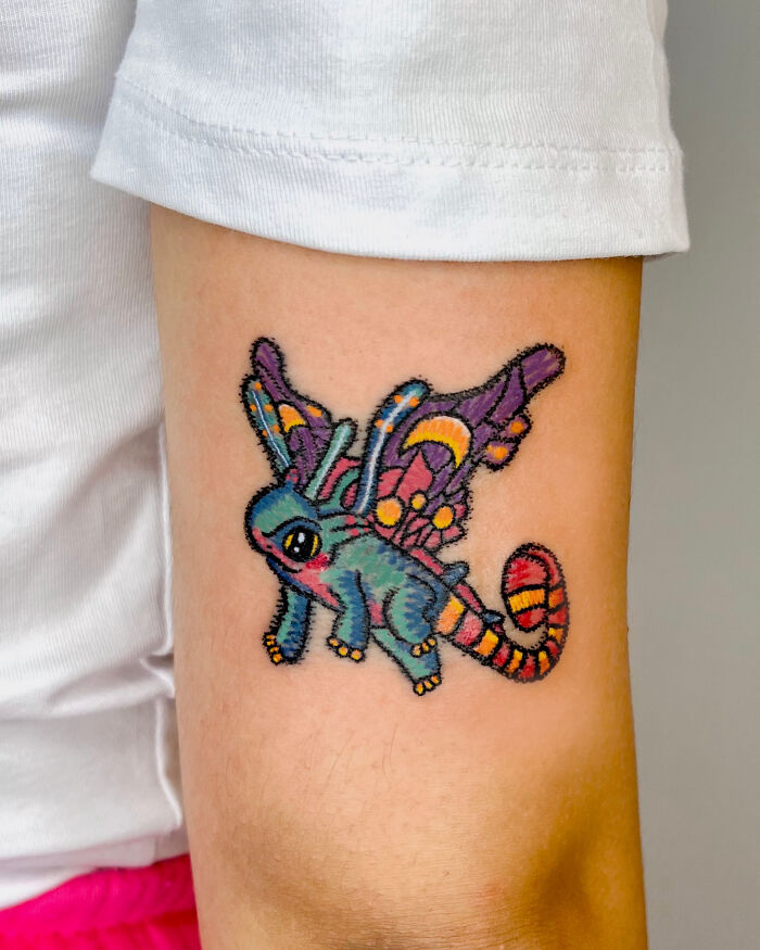 Vibrant crayon drawing-inspired tattoo of a creature with wings, showcasing unfiltered creativity.