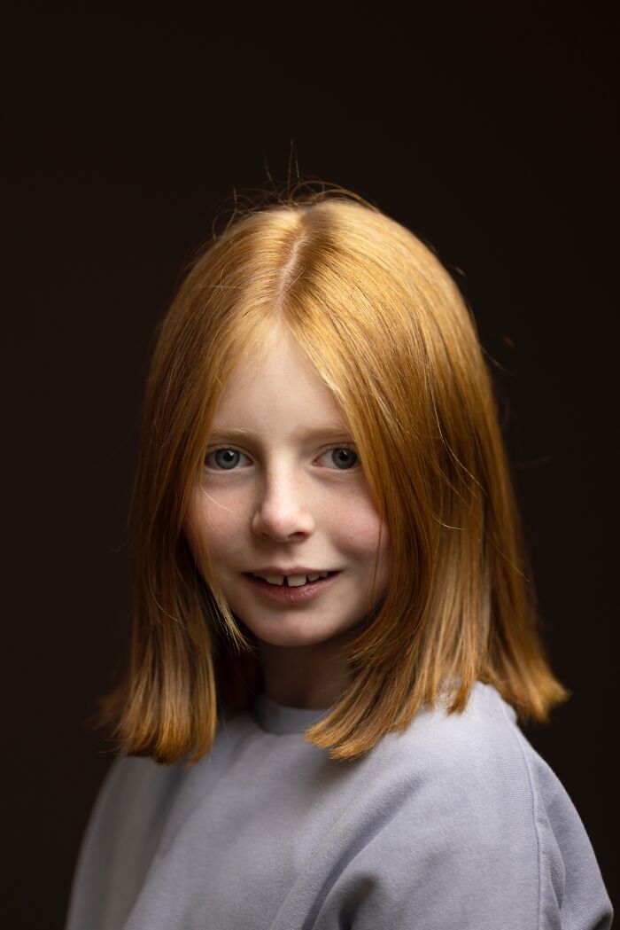 A beautiful portrait of a young natural redhead girl with a shy smile, part of a global portrait project.