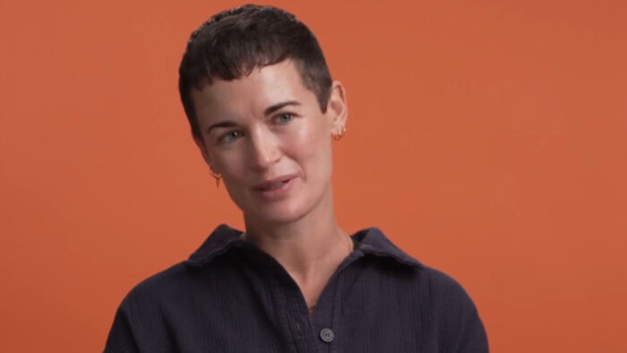 Woman with short hair smiling against an orange background, discussing movie fans reaction to plastic surgery in film. Woman with short hair smiling against an orange background, discussing movie fans reaction to plastic surgery in film.