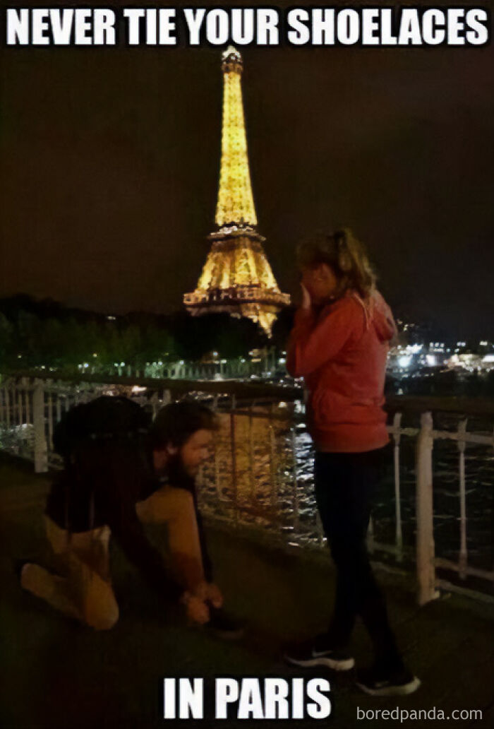 A man tying a woman's shoelace in Paris with the Eiffel Tower in the background, a funny travel meme.