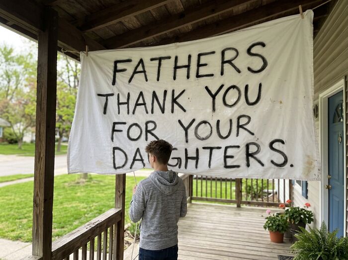 A boy stands on a porch near a banner about fathers, reflecting on his new college life world.