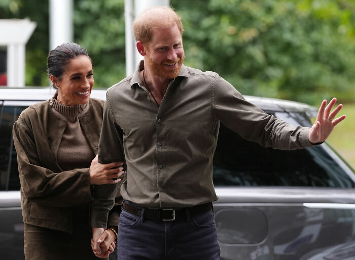 Meghan Markle and Prince Harry smile, walking hand-in-hand, during their return to UK, sparking outrage. Meghan Markle and Prince Harry smile, walking hand-in-hand, during their return to UK, sparking outrage.