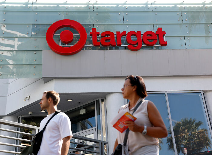 Target store exterior with its red bullseye logo prominent, people walking by, related to kids Halloween costume apology.