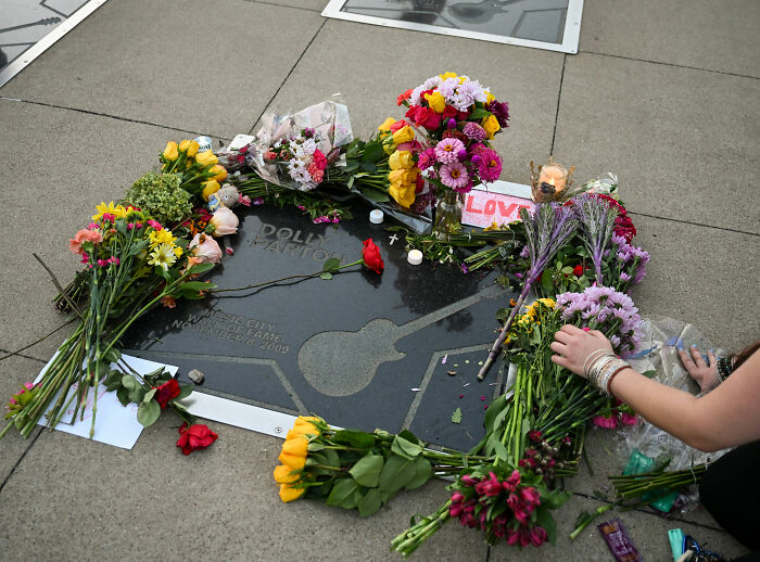 Flowers and candles laid on Dolly Parton's Music City Walk of Fame star, following news of her secret illness and passing.
