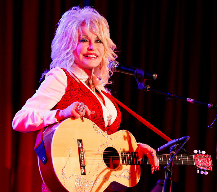 Dolly Parton on stage with guitar, revealing selfless offer to doctors during her cancer battle. Dolly Parton on stage with guitar, revealing selfless offer to doctors during her cancer battle.