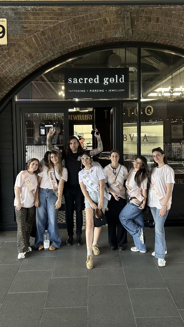 A group of friends with a tattoo artist, celebrating matching ink ideas and personal stories.
