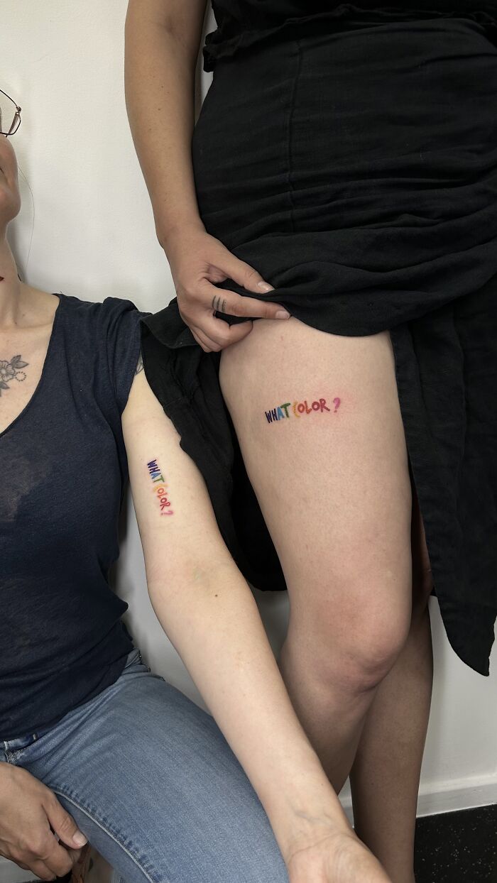 Two people with matching ink of the phrase What Color? on their arm and thigh, showcasing matching ink ideas.